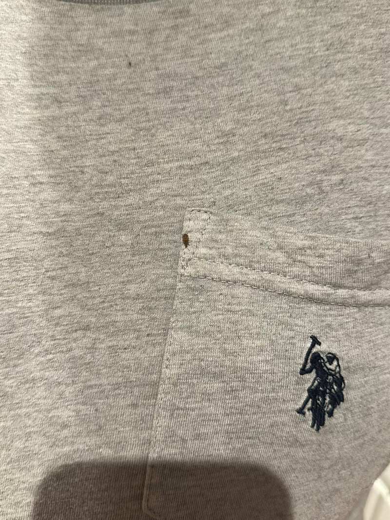 Une seule punaise de lit est assise sur un tissu gris près de la couture d'une poche de chemise. Le petit insecte est clairement visible.