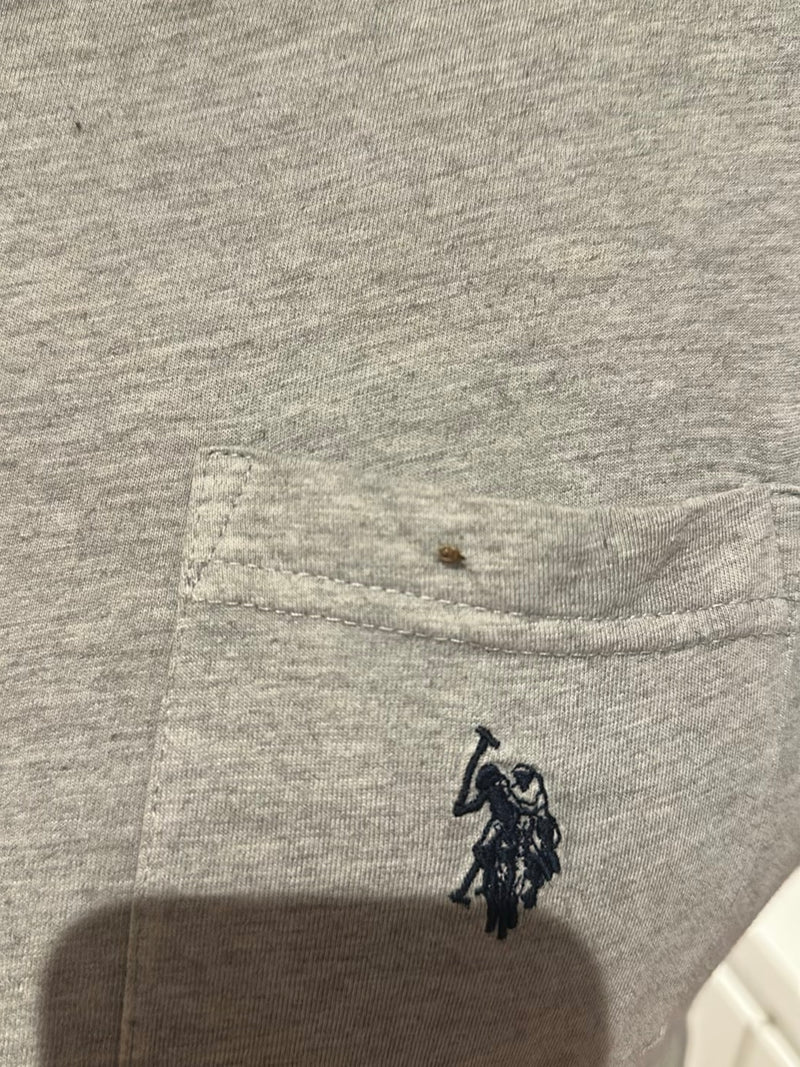 Une petite punaise de lit est assise sur un tissu textile gris avec une poche. L'insecte est très petit et à peine reconnaissable.